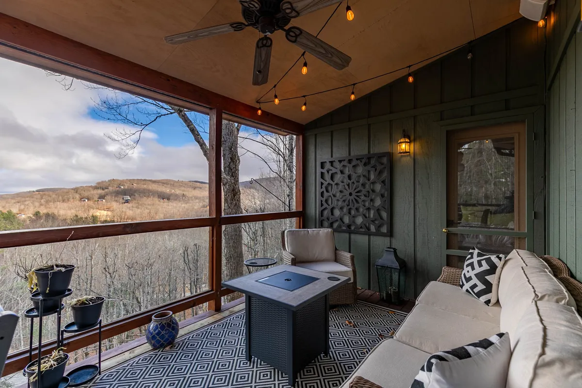 An exterior view featuring a comfortable outdoor seating area adorned with hanging lights and a decorative wall panel. The arrangement invites guests to relax and enjoy nature, offering a cozy spot for both people and pets.