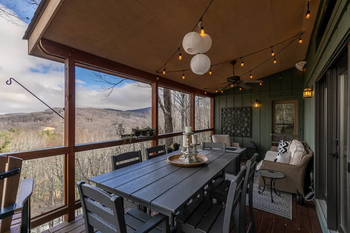 A welcoming exterior dining area with a table and hanging lanterns, offering panoramic mountain views and ample seating. The setting is serene, perfect for gathering with friends or unwinding after a day of adventure.