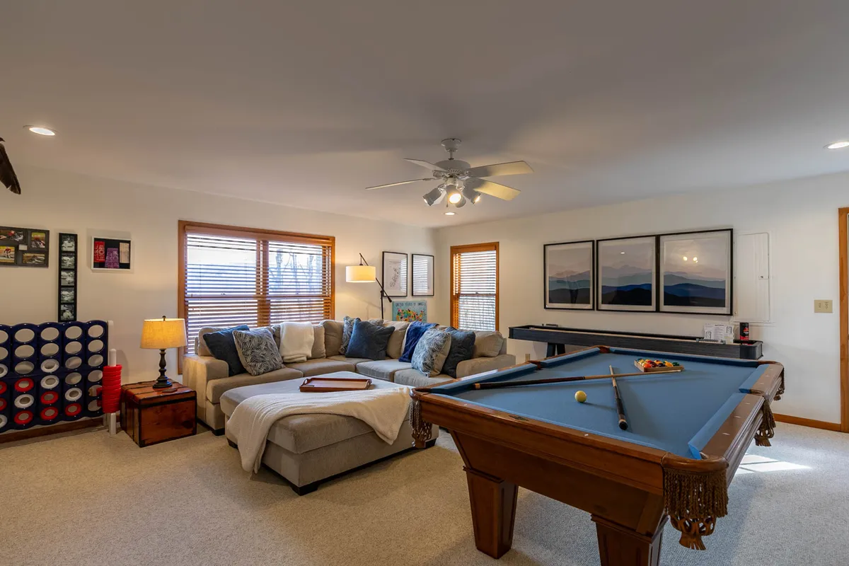 A vibrant game room featuring a classic pool table as the focal point, with a comfortable sofa set nearby. Artworks and lamps on the walls add a touch of style, creating an inviting atmosphere for games, relaxation, and socializing.